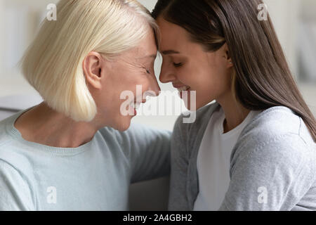 Gerne ältere Frau berühren Stirnen mit attraktiven Tochter. Stockfoto