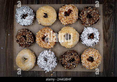 Ganache glasierte Krapfen, mit verschiedenen zerkleinerten Nüssen bestreut Stockfoto