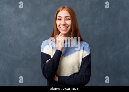 Junge Mädchen in warmen Blau Pullover an der Wand isoliert. Stockfoto