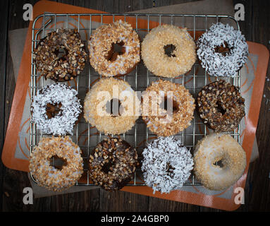 Ganache glasierte Krapfen, mit verschiedenen zerkleinerten Nüssen bestreut Stockfoto