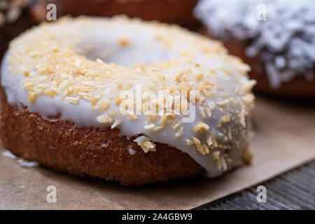 Ganache glasierte Krapfen, mit verschiedenen zerkleinerten Nüssen bestreut Stockfoto