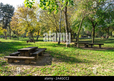 Picknick Tische und Bänke auf der grünen Wiese unter den Bäumen in Bunden City Park, Zagreb, Kroatien Stockfoto