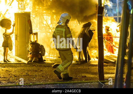 Feuerwehrleute rund um ein Feuer, verursacht durch eine Falla Valenciana Controlling die Flammen des Feuers. Stockfoto