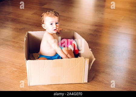 Baby Mädchen spielen, der in einer Kartonage verpackt mit Hilfe ihrer Phantasie. Stockfoto