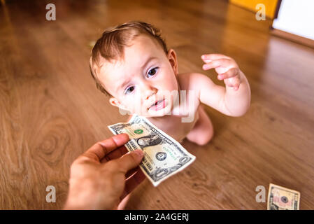 Baby erreichen einige Dollarscheine, verschwendet Familie Einsparungen Konzept Stockfoto