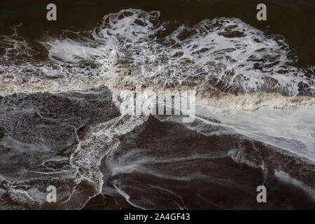 Brechende Wellen erzeugen Muster auf Strand Stockfoto