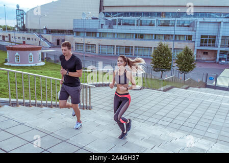 Athletisch Paar Mann und schöne Frau, im Sommer in der Stadt, laufen Joggen auf Treppen, freier Platz für Text motivation Fitness und Workout, Sportbekleidung. Stockfoto