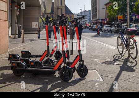 Gruppe von E-Scooter von Start-up-Unternehmen mit der Idee der Umweltfreundliche Mobilität für urbanen Lebensstil und durch die gemeinsame Nutzung von Elektroroller, Park auf schattigen Bürgersteig. Stockfoto