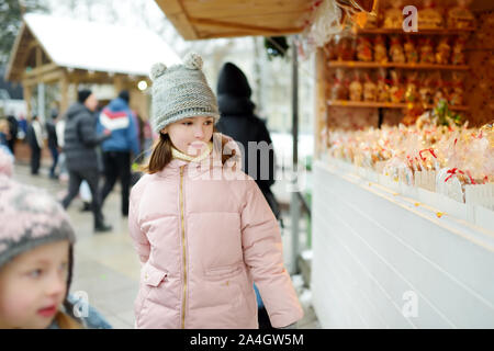 Junge Mädchen an Weihnachten Puppen und Dekorationen am Weihnachtsmarkt in Vilnius, Litauen verkauft. Dekoriert und beleuchtet Shopping steht mit v Stockfoto