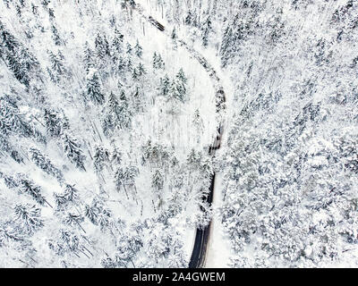 Schöne Luftaufnahme von verschneiten Wäldern und einer Straße Wicklung unter Bäumen. Rime Eis und Raureif auf den Bäumen. Malerische Winterlandschaft Nea Stockfoto