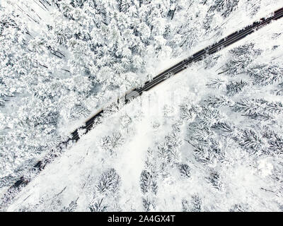 Schöne Luftaufnahme von verschneiten Wäldern und einer Straße Wicklung unter Bäumen. Rime Eis und Raureif auf den Bäumen. Malerische Winterlandschaft Nea Stockfoto