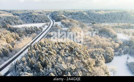 Schöne Luftaufnahme von verschneiten Wäldern und einer Straße Wicklung unter Bäumen. Rime Eis und Raureif auf den Bäumen. Malerische Winterlandschaft Nea Stockfoto