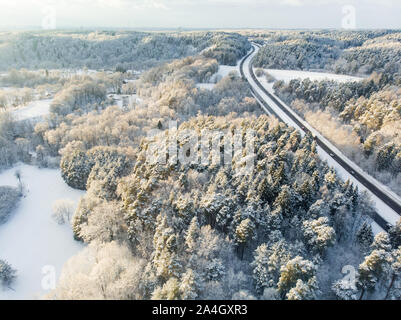 Schöne Luftaufnahme von verschneiten Wäldern und einer Straße Wicklung unter Bäumen. Rime Eis und Raureif auf den Bäumen. Malerische Winterlandschaft Nea Stockfoto