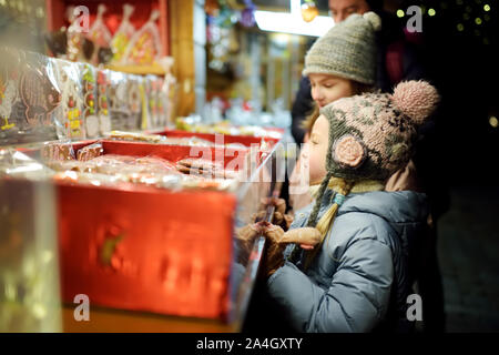 Nette junge Schwestern Spezialitäten Auswahl auf den traditionellen Weihnachtsmarkt in Riga, Lettland. Kinder kaufen Candy und Cookies auf Weihnachten. Happy Family Zeit an kühlen Stockfoto