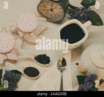 Eine Tabelle mit gerösteten und gemahlenen Kaffee, amerikanischen Kaffee und heiße Milch bereit, um bedient zu werden, zusammen mit den Gläsern von Honig und Blumen an jedem Morgen Stockfoto