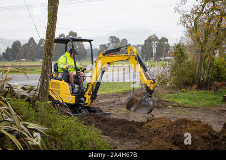 Ein Erbauer gräbt ein Graben auf einer Baustelle, die Wasser- und Stromversorgung Kabel in Canterbury, Neuseeland zu legen Stockfoto