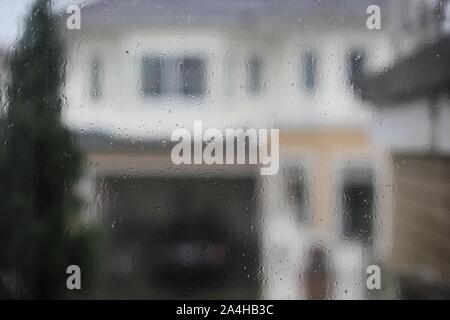 Regen Wassertropfen spritzen auf Glas Fenster gefangen. im Regen zu Hause gefangen. Stockfoto