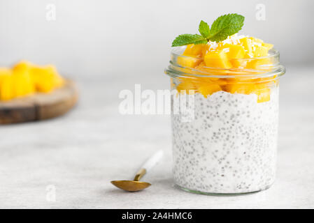 Chia Pudding mit Mango in den jar auf grauem Beton Hintergrund. Saubere Konzept Essen, gesunde vegetarische Kost Stockfoto