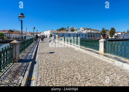 Fußgängerzone Kopfsteinpflaster Brücke wissen als Römische Brücke (Puente Romano) die Gilao Fluss überquert. Tavira, Algarve, Portugal, April 2019 Stockfoto