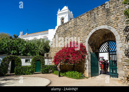 Eingang der mittelalterlichen Burg von Tavira (Castelo de Tavira) mit der St. Mary's Kirche (Igreja Santa Maria do Castelo) im Hintergrund, Algarve, Portuga Stockfoto