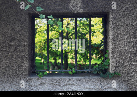 Stein Wand mit Fenster mit Gittern und Blick auf blurry Jüdischen Friedhof im Hintergrund Stockfoto