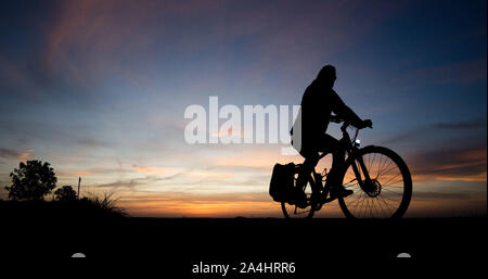 Hannover, Deutschland. 15 Okt, 2019. Ein Mann reitet ein Fahrrad entlang einem Feldweg kurz nach Sonnenaufgang. Credit: Julian Stratenschulte/dpa/Alamy leben Nachrichten Stockfoto