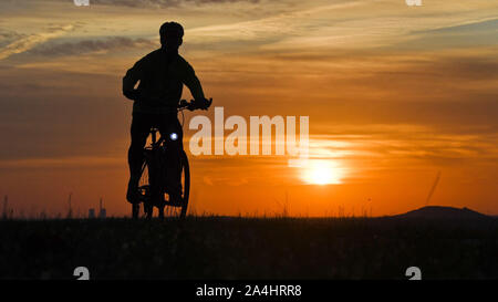 Hannover, Deutschland. 15 Okt, 2019. Ein Mann reitet ein Fahrrad entlang einem Feldweg kurz nach Sonnenaufgang. Credit: Julian Stratenschulte/dpa/Alamy leben Nachrichten Stockfoto
