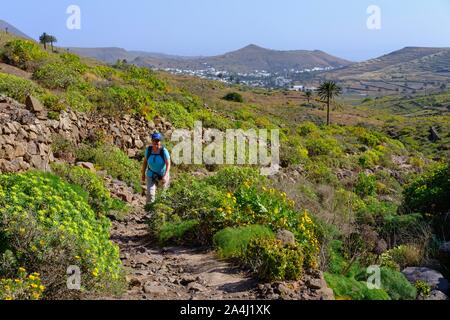 Frau geht auf Wanderweg durch steinige Landschaft, in der Nähe von Haria, Lanzarote, Kanarische Inseln, Spanien Stockfoto