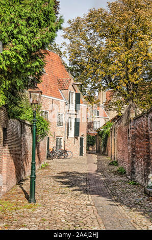 Middelburg, Niederlande, 9. Oktober 2019: Schmale, mit Kopfstein gepflasterte Straße zwischen Mauern in der Altstadt, mit einem historischen lantrn und Bäume Herbst Stockfoto