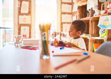 Schöne afrikanische amerikanische Kleinkind spielen mit Dinosaurier Spielzeug auf dem Schreibtisch im Kindergarten Stockfoto