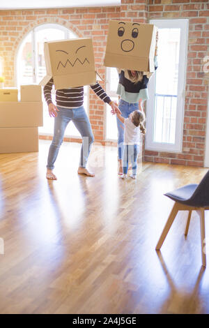 Schöne famiily mit Kid spielen mit Pappe fanny Boxen im neuen Zuhause Stockfoto