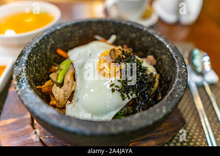 Detailansicht eines leckeren würzig und lecker Sizzling koreanischen Bibimbap in einem heißen Stein Schüssel Stockfoto