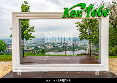 Almaty Kok Tobe Blue Hill Mountain Park Inschrift Rahmen des Stadtbildes an einem nebligen und trüben Tag Stockfoto