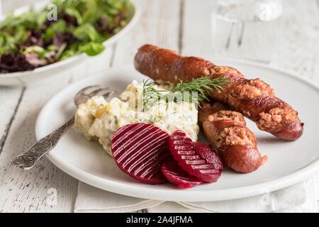 Isterband Wurst mit Dill geschmorte Kartoffeln und eingelegte Rote Bete, traditionelle schwedische Küche. Auf einem weißen Tisch, mit einem grünen Salat in den hinterg Stockfoto