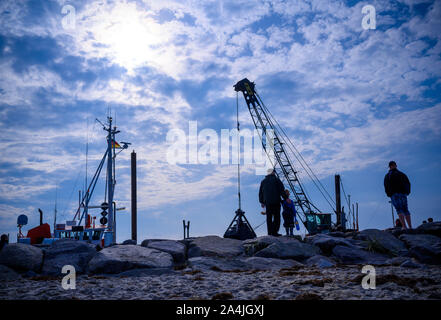 13. Oktober 2019, Mecklenburg-Vorpommern, Timmendorf (Insel Poel): Wanderer beobachten, die Arbeit auf dem Schiff bin arete Chris' aus Dänemark, das Ausbaggern der Hafenbecken. Neben der Pilot Boot und Fischerboote, zahlreiche Segelboote und Motoryachten mit der kleinen Hafen auf der Ostsee Insel Poel im Sommer. Foto: Jens Büttner/dpa-Zentralbild/ZB Stockfoto