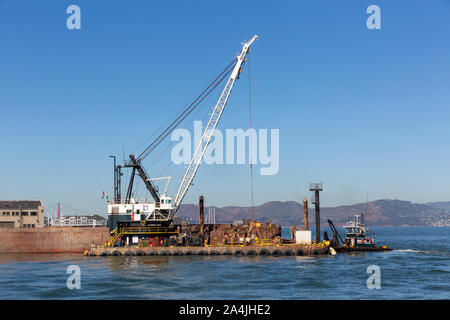 SAN FRANCISCO, USA - OKTOBER 2, 2019: baggerarbeiten Kran und Kahn am Ende der Pier 35 in San Francisco Bay. Stockfoto