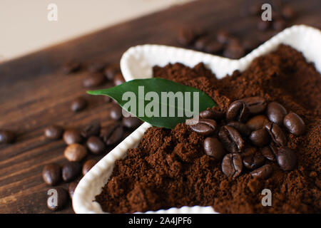Gemahlener Kaffee in einer weißen Schüssel auf einem Holzbrett. Stockfoto