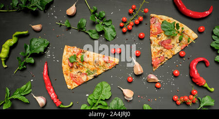 Dreieckige Stück Pizza mit Pilzen, geräucherte Wurst, Tomaten und Käse, schwarzer Hintergrund, flach Stockfoto