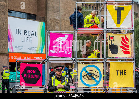 London, Großbritannien. 15 Okt, 2019. Aussterben Rebellion einrichten Strukturen outsde der Vorderseite des Tate Modern, wie in der Vorschau des Nam June Paik exhibitiongoes auf der Innenseite. Sie sind schnell von der Stadt London Polizei umgeben und mit Verhaftung gedroht, wenn sie nicht kommen. Credit: Guy Bell/Alamy leben Nachrichten Stockfoto