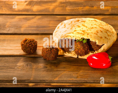 Falafelkugeln, Pita-arabischen Brot und frischem Gemüse auf einem hölzernen Hintergrund. Falafel spielt eine Ikonischen Rolle in der israelischen Küche und ist weithin als das nationale Gericht des Landes zu sein. Stockfoto