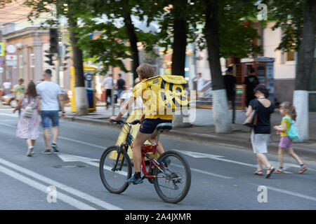 KRASNODAR, Russland, 10. AUGUST 2019: junger Kerl, essen Lieferung Junge, Fahrten mit dem Fahrrad auf der Straße in der Mitte der Stadt Stockfoto