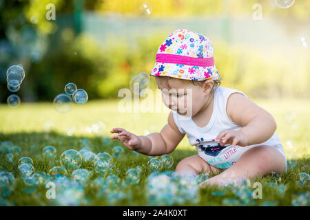 Babysitting auf Rasen und amüsant zu spielen mit Luftblasen. Stockfoto