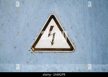 Hohe Spannung Warndreieck Zeichen auf Grunge graues Metall an der Wand montiert Stockfoto