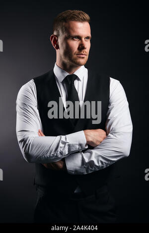 Schwere angenehm starker Mann in der Mode Shirt, Weste und Krawatte seine Arme zur Seite schauen, Kreuzung, Nahaufnahme, isolierte schwarze backgrround, Studio gedreht. Stockfoto