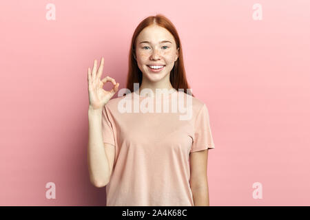 Junge positive attraktive Teenager zeigen ok Zeichen mit Fingern. Isolierte rosa Hintergrund, studio Shot, Gestik, Körpersprache, alles ist ok Stockfoto