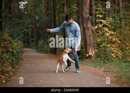 Fröhlicher junger Mann Spaß mit Hund in den Wald, Freundschaft, Unterhaltung. volle Länge Foto Stockfoto