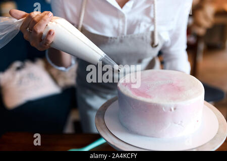 Schule des Kochens Kuchen, bis 7/8 Foto schließen. die Frau mit einer Tasche, die Creme auf die Kuchen anzuwenden Stockfoto