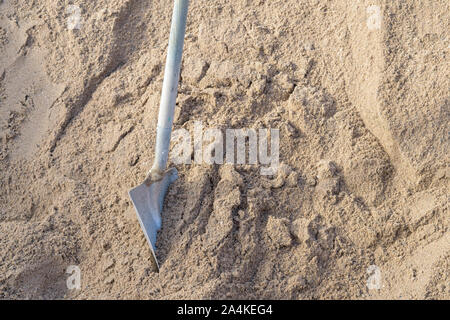 Ein Spaten steht in einem Haufen Sand auf einem Bauvorhaben. Stockfoto