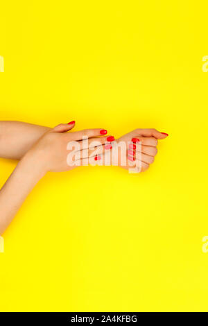 Stilvoll trendy Rot weibliche Maniküre. Die Hand einer schönen Frau auf einem gelben Hintergrund. Stockfoto