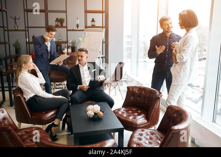 Junge entspannt positiven Menschen in formalen stilvolle Kleidung in eine Pause am Arbeitsplatz, geschäftige Atmosphäre im Büro Zimmer Stockfoto